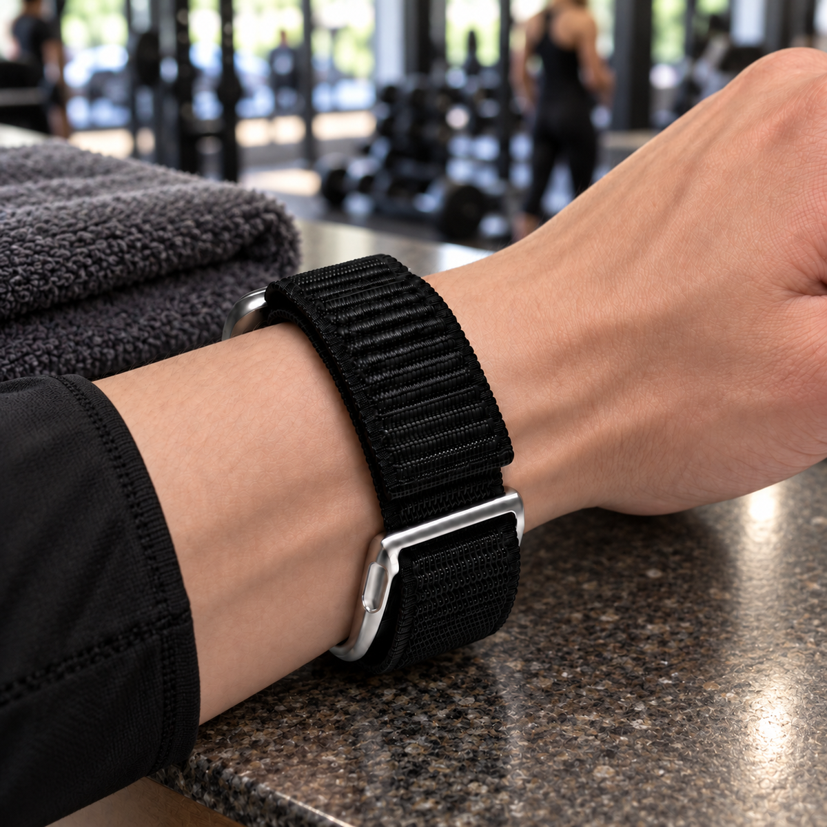 Black SYNCRBAND nylon band and silver WHOOP-side frame on a wrist in an illustrative gym setting