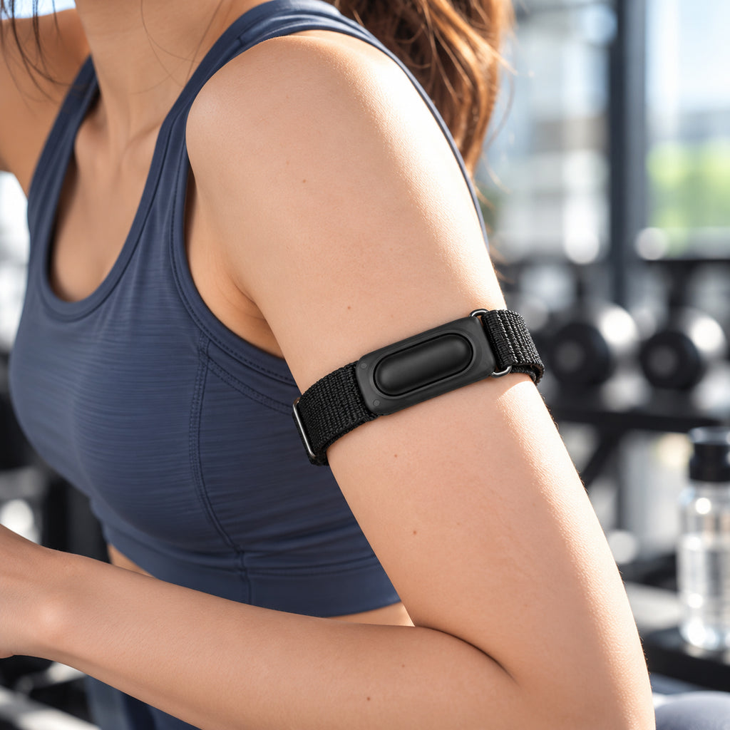 Black Fitbit Air nylon armband worn on the upper arm during a gym session; device not included
